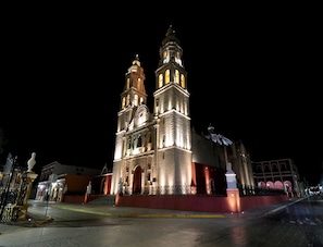 A historic building with two prominent towers and a central dome, illuminated at night.
