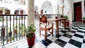 Un balcón con suelo a cuadros, muebles de madera y plantas en macetas.