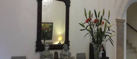 A room with a wooden console table, a mirror, and a vase with flowers.