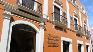 Fachada de hotel con una amplia entrada arqueada, balcones con barandillas de hierro forjado y un letrero que indica el nombre del hotel.