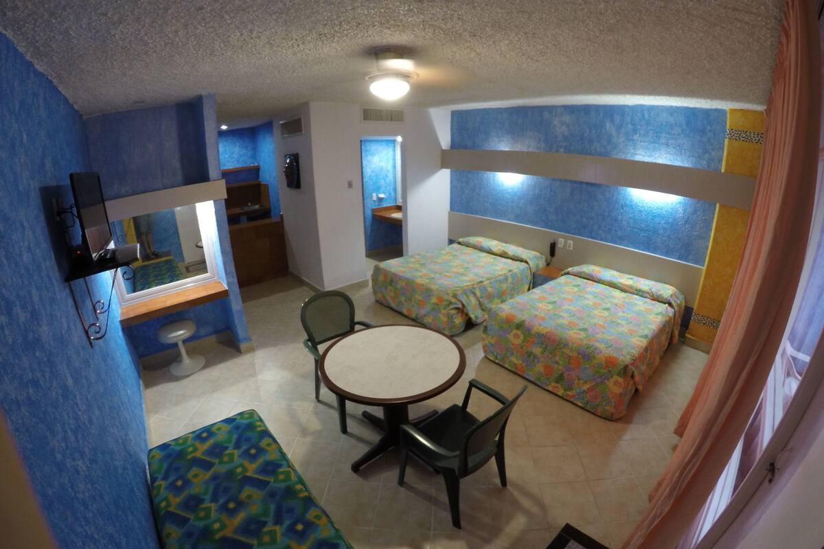 Una habitación con dos camas, una mesa redonda y una silla.