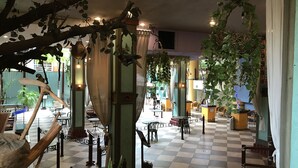 Ein geräumiger Innenbereich mit Schachbrettmuster-Bodenbelag, verschiedenen Sitzgelegenheiten und Zierpflanzen.