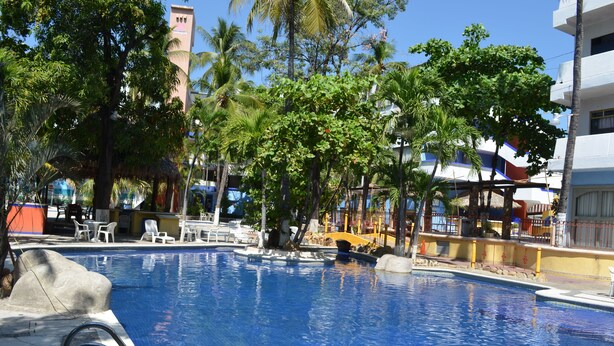 Ein Swimmingpool mit Liegestühlen und Palmen.