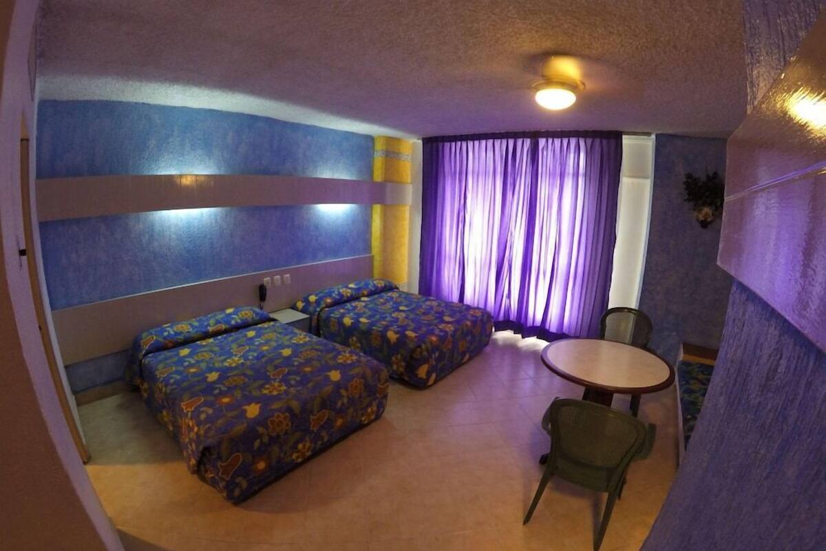 Una habitación con dos camas, una mesita y una silla.