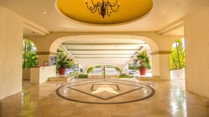 A spacious lobby with a central chandelier, a star-patterned floor, and potted plants.