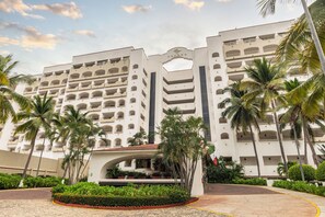 A multi-story hotel with balconies, palm trees, and a central archway. - Tesoro Ixtapa All Inclusive (Ixtapa)