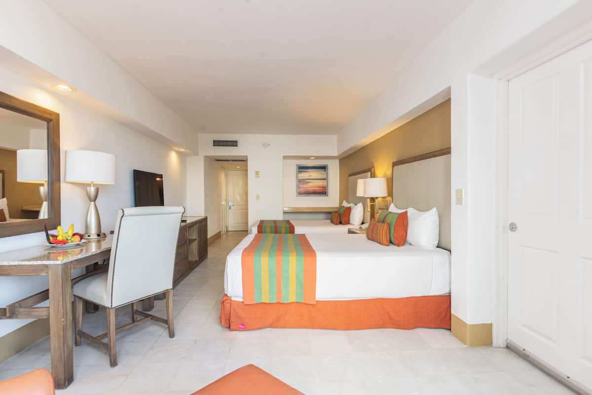 A hotel room with a bed, a desk, a chair, a mirror, and a painting on the wall.