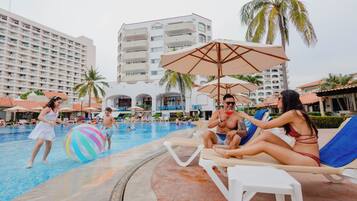 Relax by the pool surrounded by palm trees and comfortable lounge chairs under shaded umbrellas.