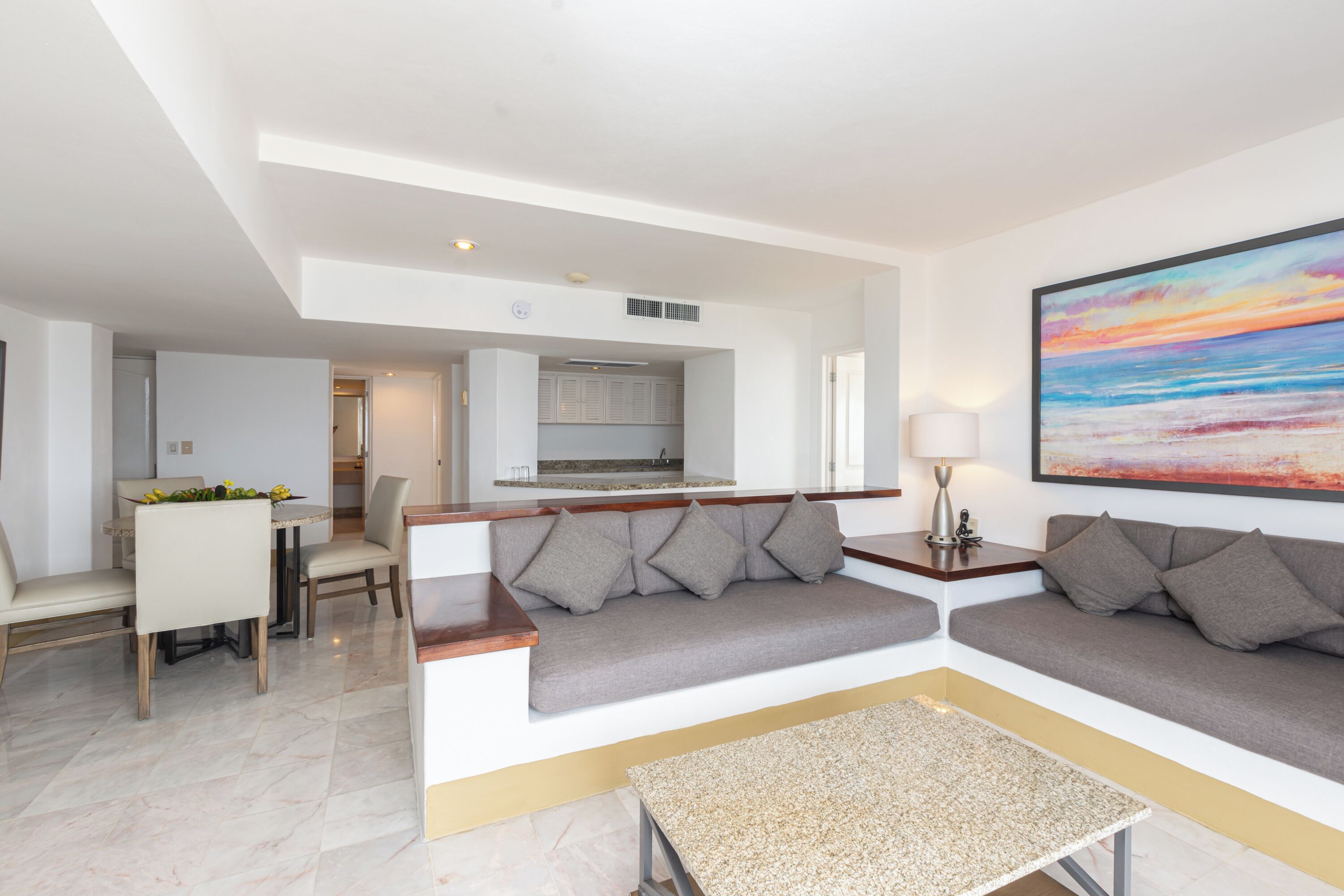 A modern living room with a sofa, a coffee table, and a dining area with chairs.