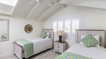 A bedroom with two beds, a ceiling fan, a nightstand, and a window with blinds.
