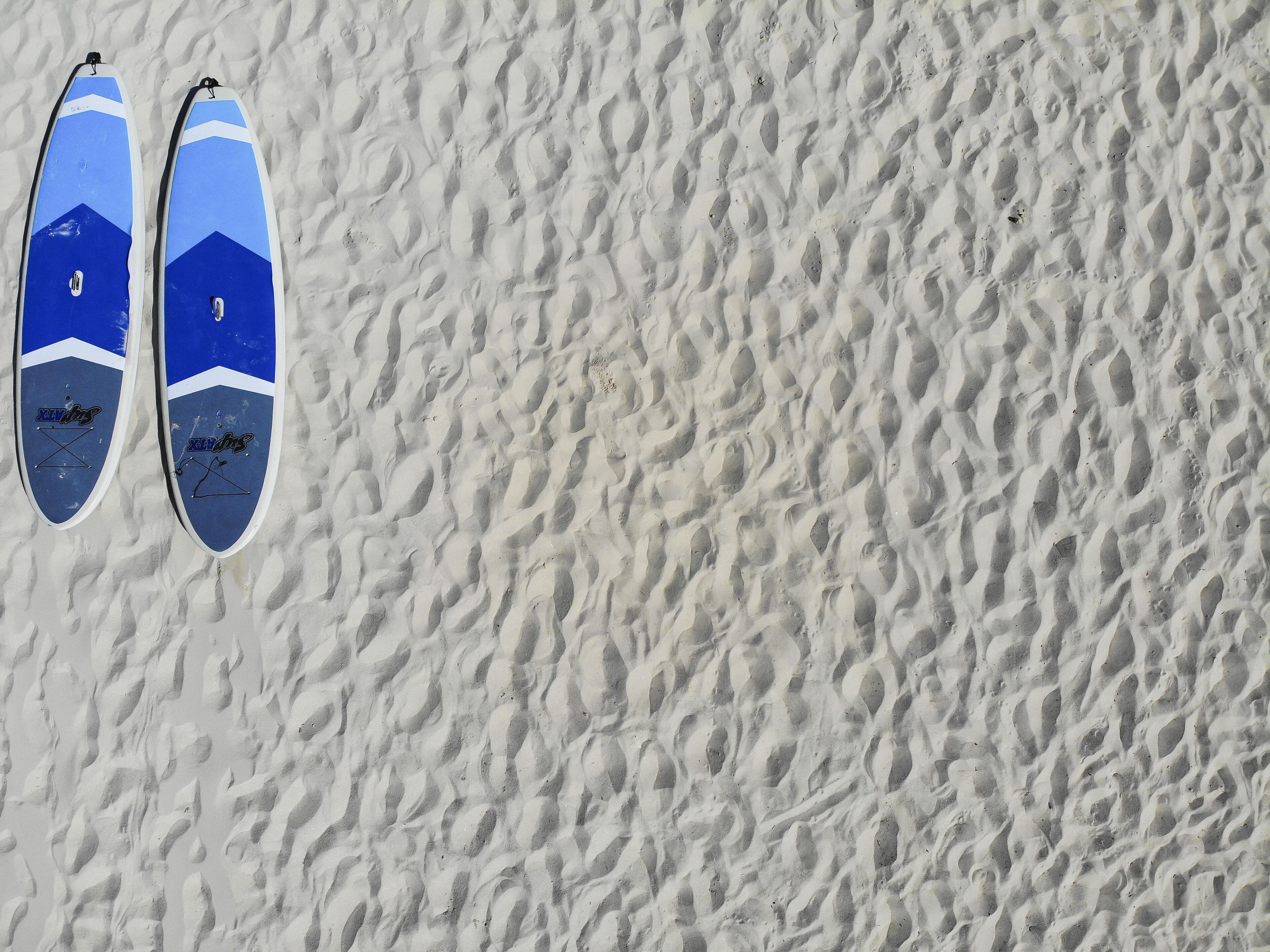Deux planches de surf sur une surface sablonneuse à la texture particulière.