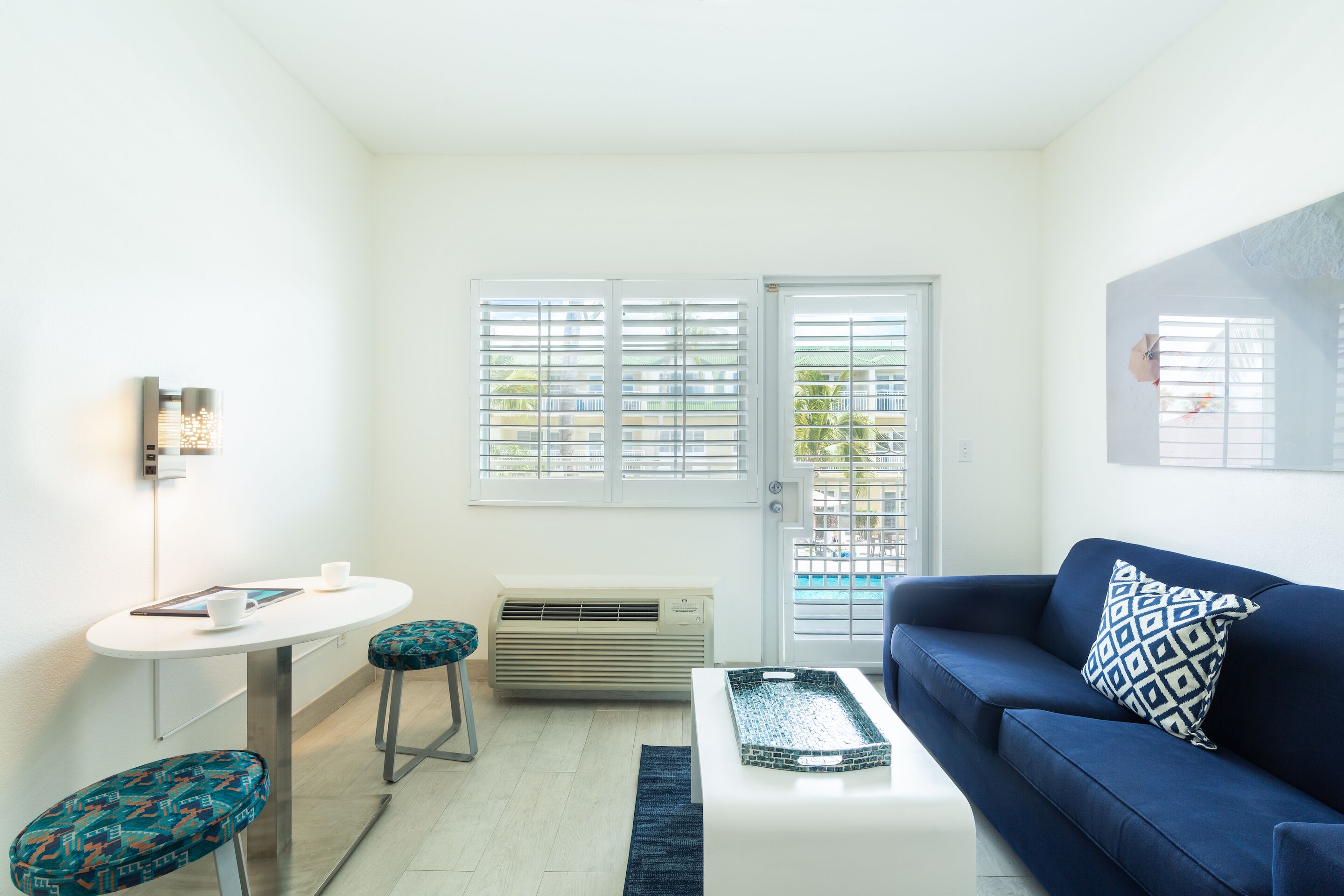 Ein modernes Wohnzimmer mit einem blauen Sofa, einem weißen Couchtisch und einem kleinen runden Tisch mit zwei Stühlen.