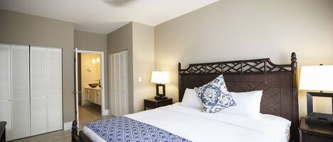 A hotel room with a large bed, a wooden headboard, a nightstand with a lamp, and a ceiling fan.