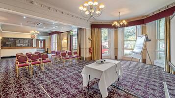 Una sala de conferencias con alfombra estampada, una mesa blanca y un proyector.