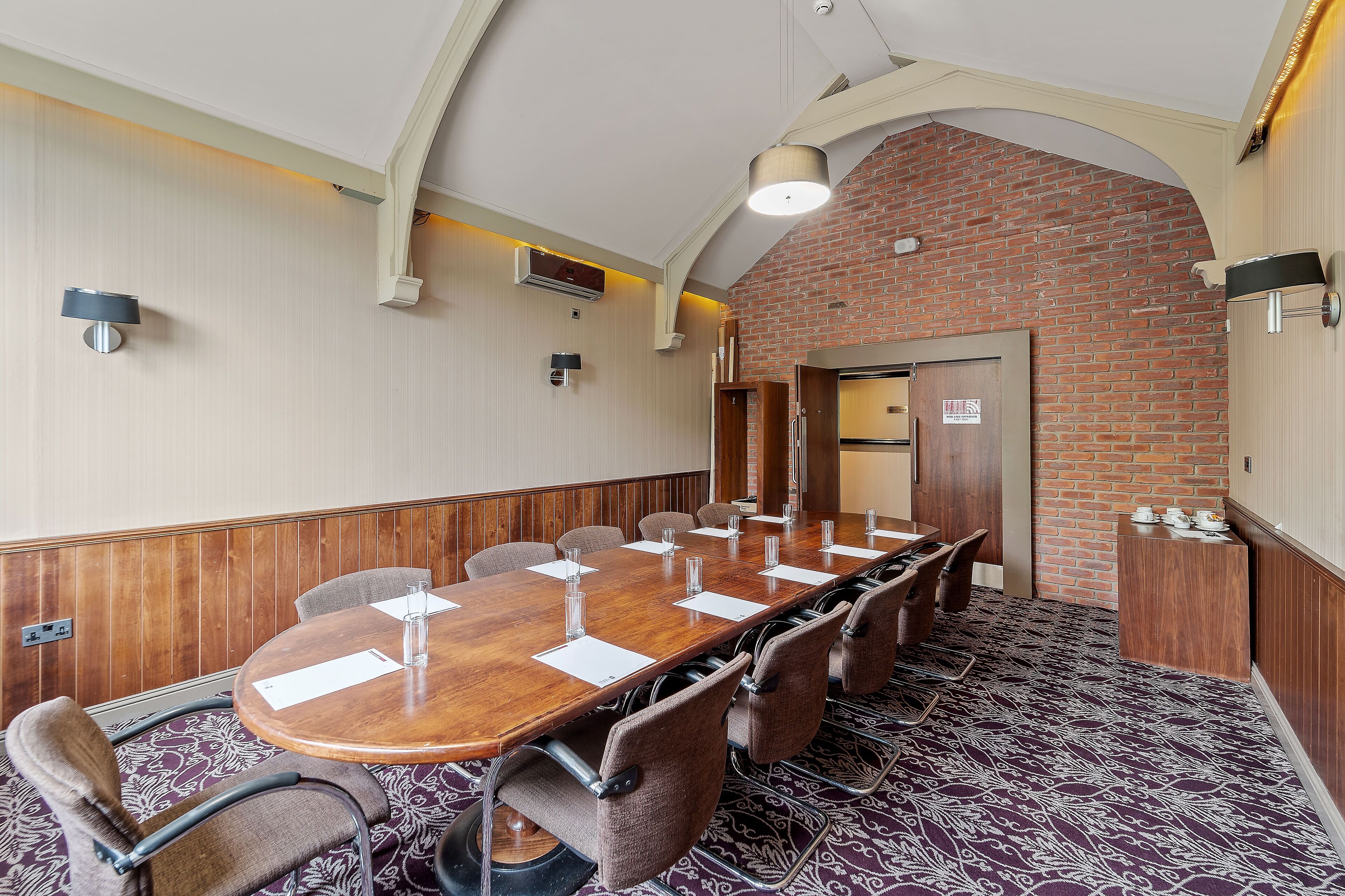 A conference room with a long table, chairs, and a patterned carpet.