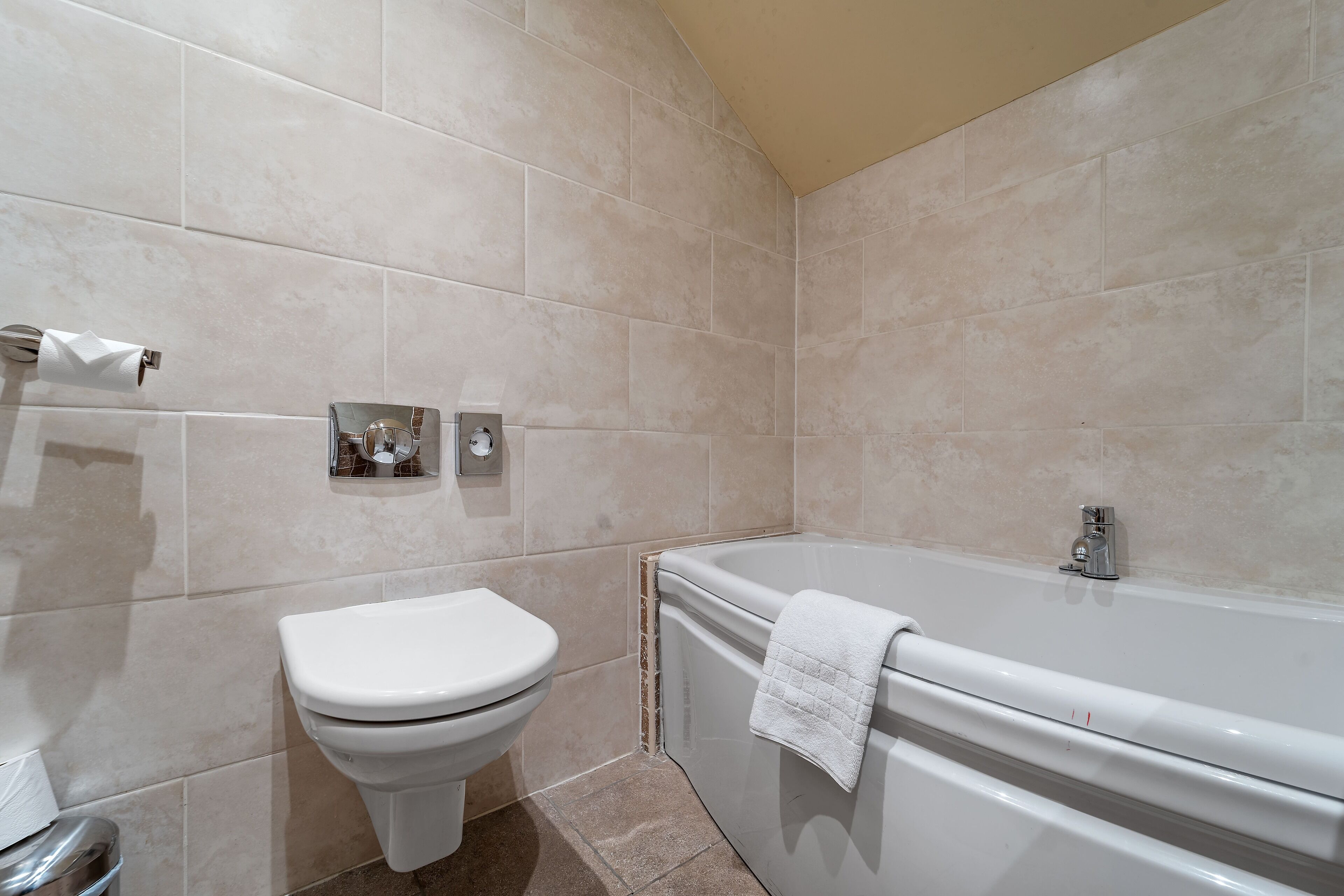 A bathroom with a toilet, a bathtub, and a towel rack.