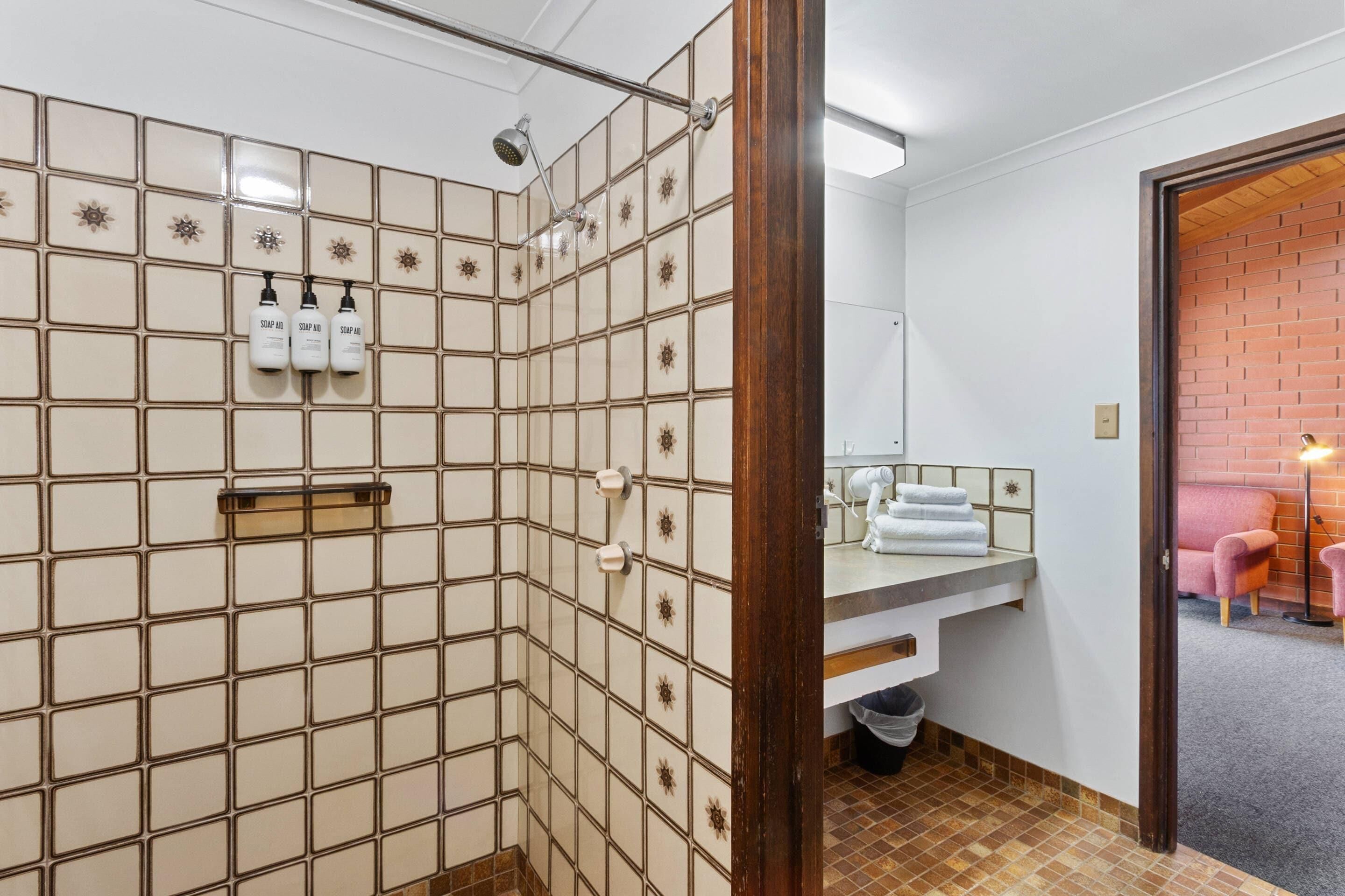 Une salle de bain avec une douche, un lavabo avec un miroir et un porte-serviettes.