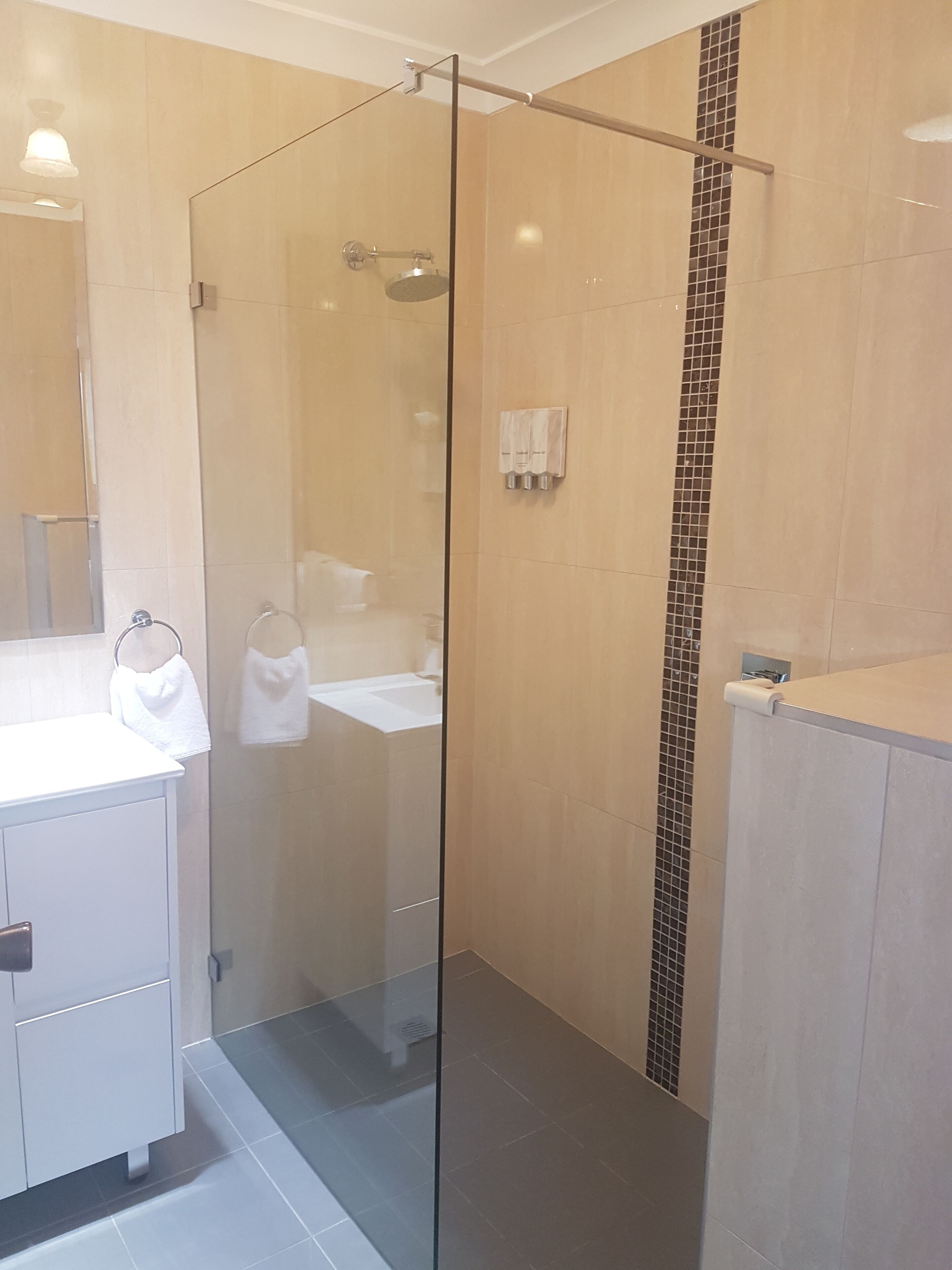 A modern bathroom with a glass-enclosed shower, a white sink, and a mirror.