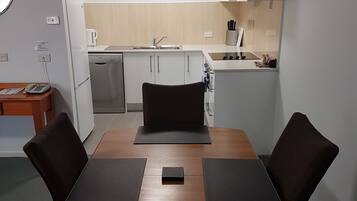 A compact kitchen with a sink, stove, and a clock on the wall.