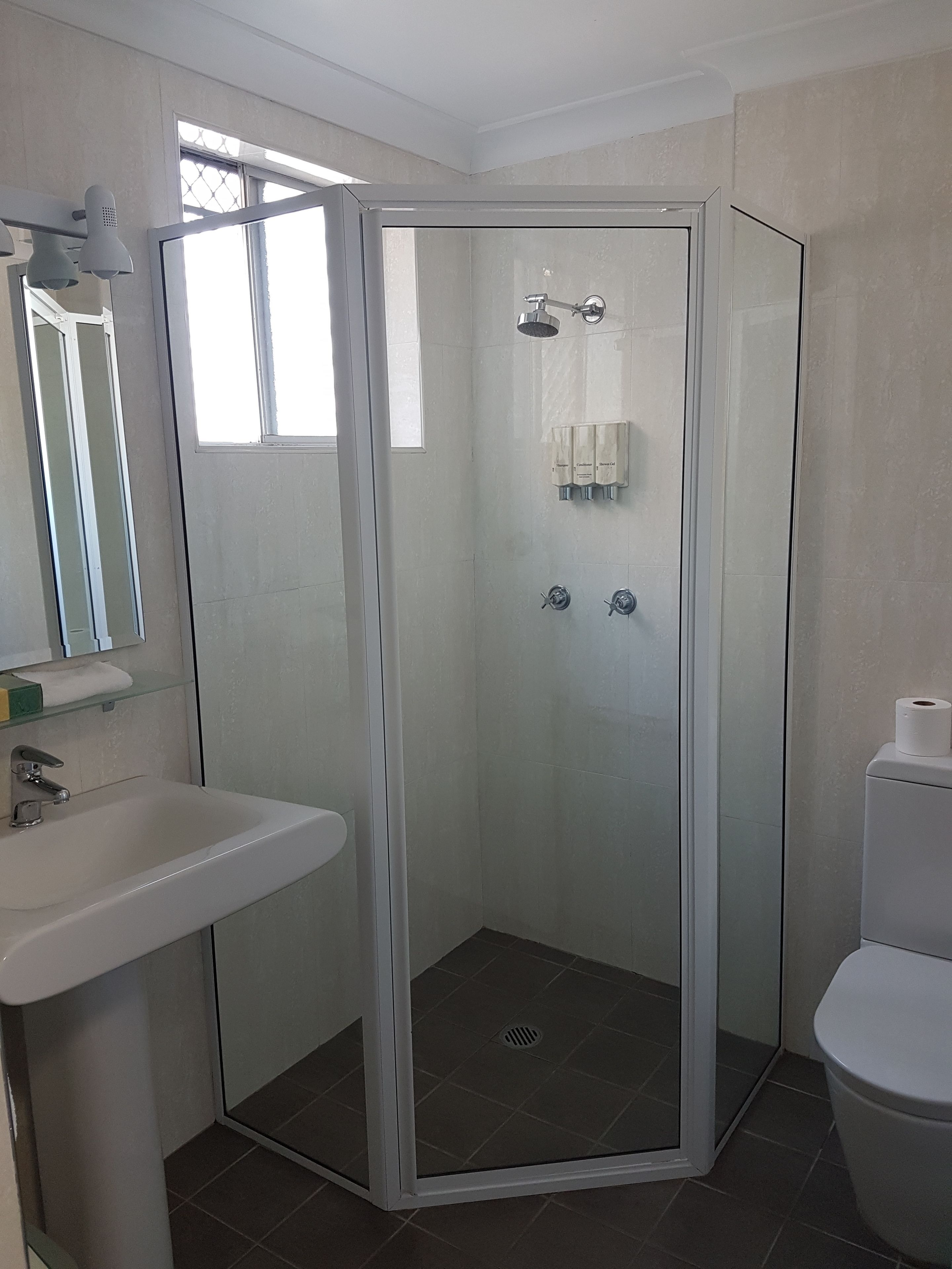 Uma casa de banho moderna com cabine de duche em vidro, lavatório e sanita.