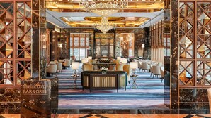 Un interior lujoso del Gordon Ramsay Bar & Grill, con suelos de mármol, muebles elegantes y una araña.