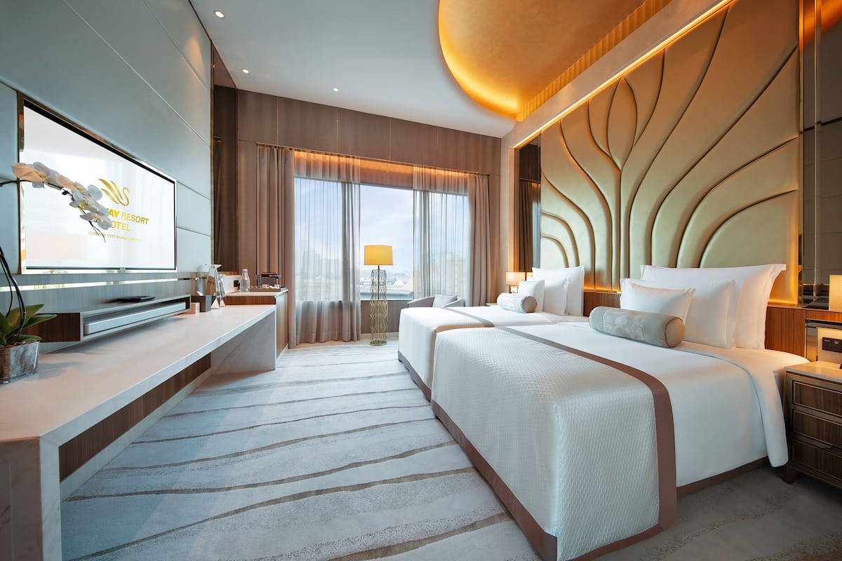 A modern hotel room with a large bed, a desk, and a television.