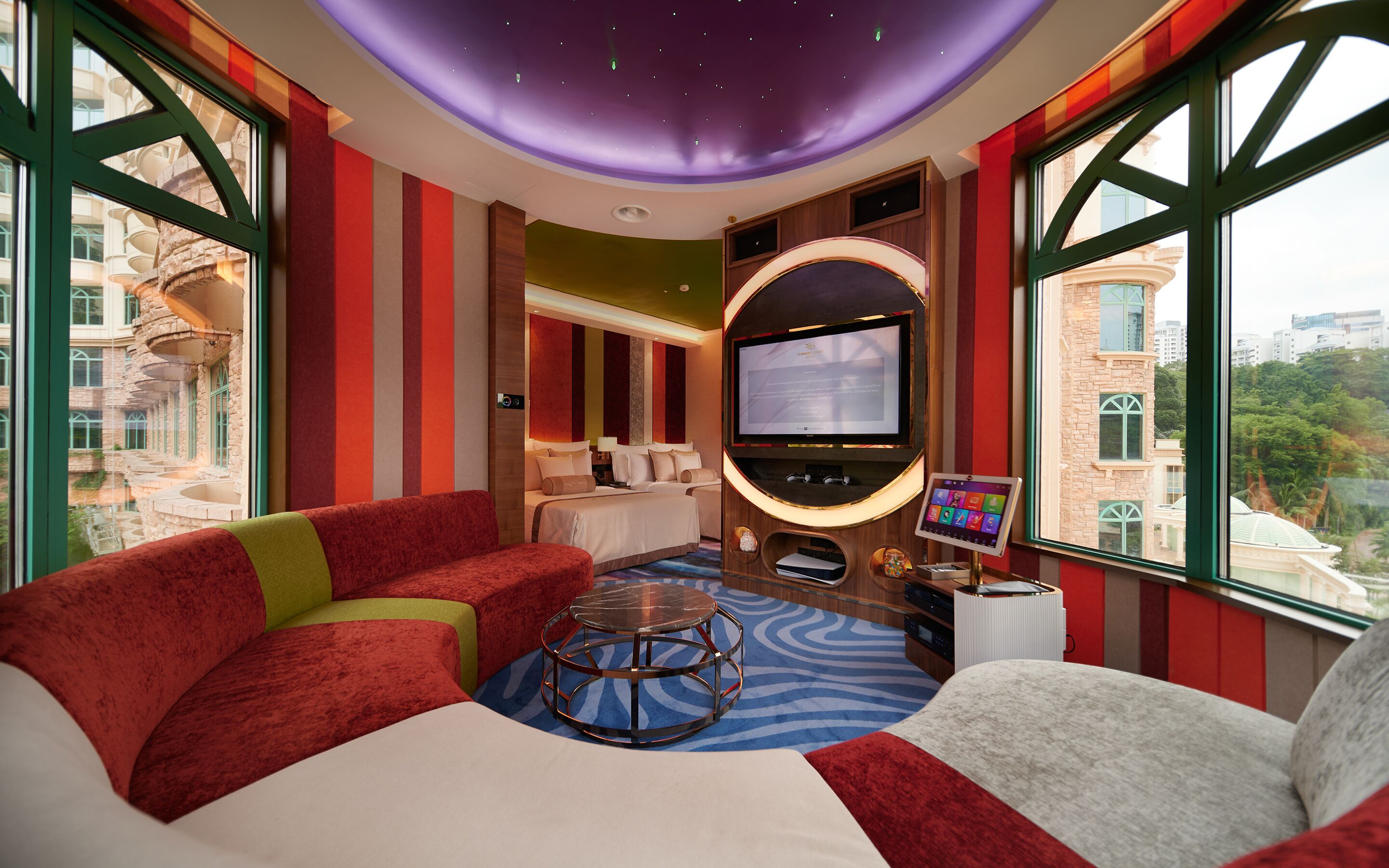 Habitación de hotel con una cama grande, televisión, ordenador portátil y vistas a la ciudad.