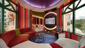 Habitación de hotel con una cama grande, televisión, ordenador portátil y vistas a la ciudad.