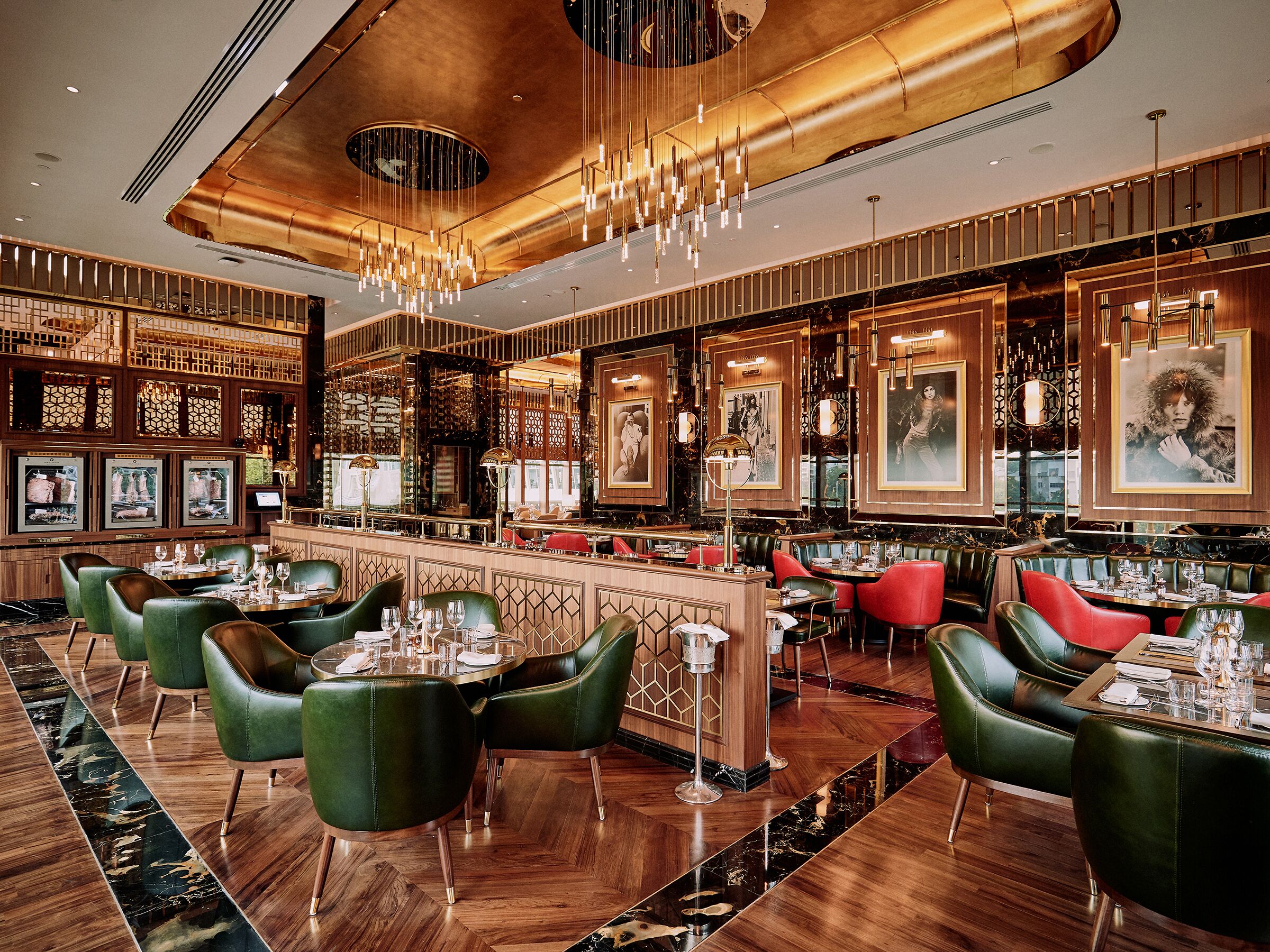 A restaurant with a bar area, green upholstered chairs, and a wooden floor.