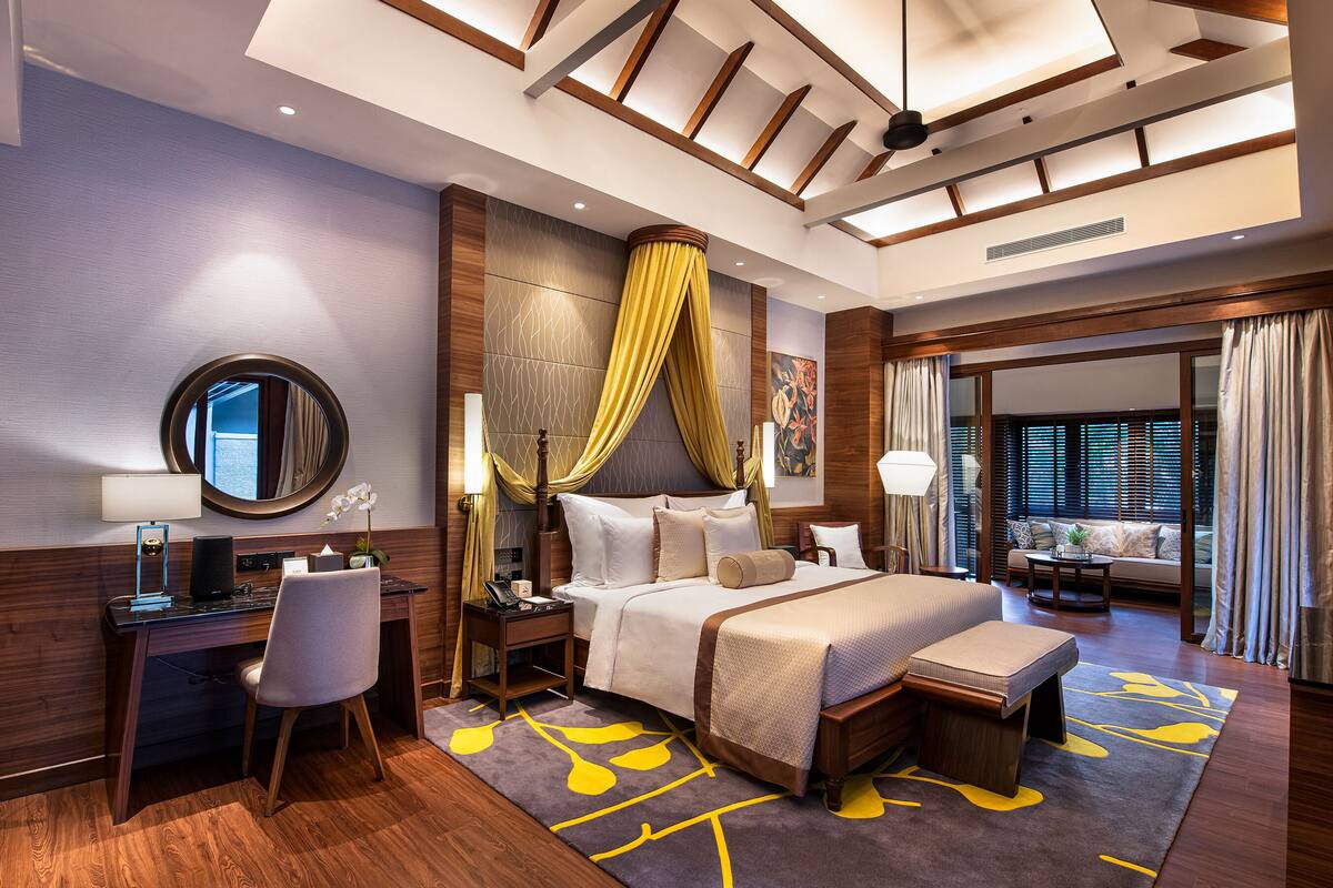 A modern hotel room with a large bed, a desk, and a seating area with a view.