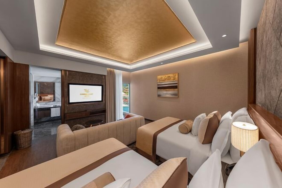 Una habitación de hotel con televisión, sofá, cama y lámpara.