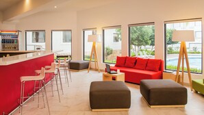 A modern hotel lobby with a bar area, seating, and large windows offering views of the outdoors. - Fiesta Inn Express Monclova (Monclova)