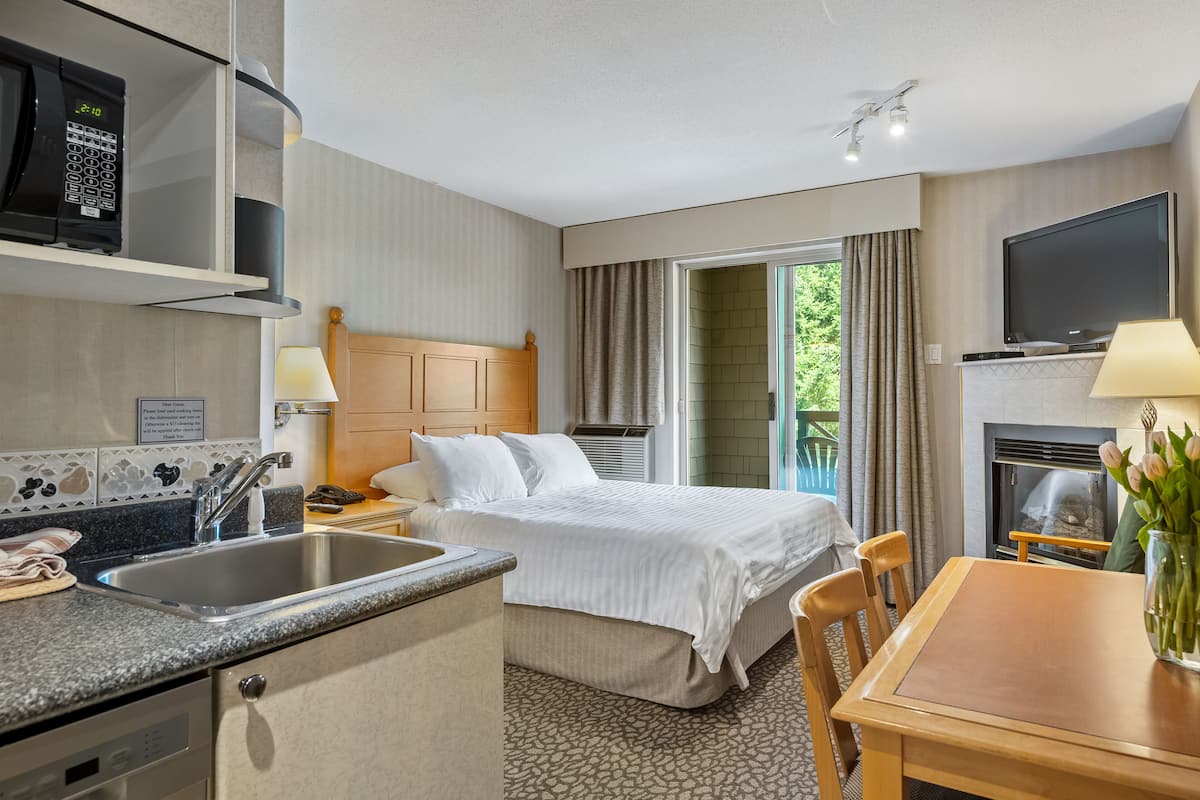 Een hotelkamer met een bed, een bureau, een televisie, een open haard, een wastafel en een magnetron.