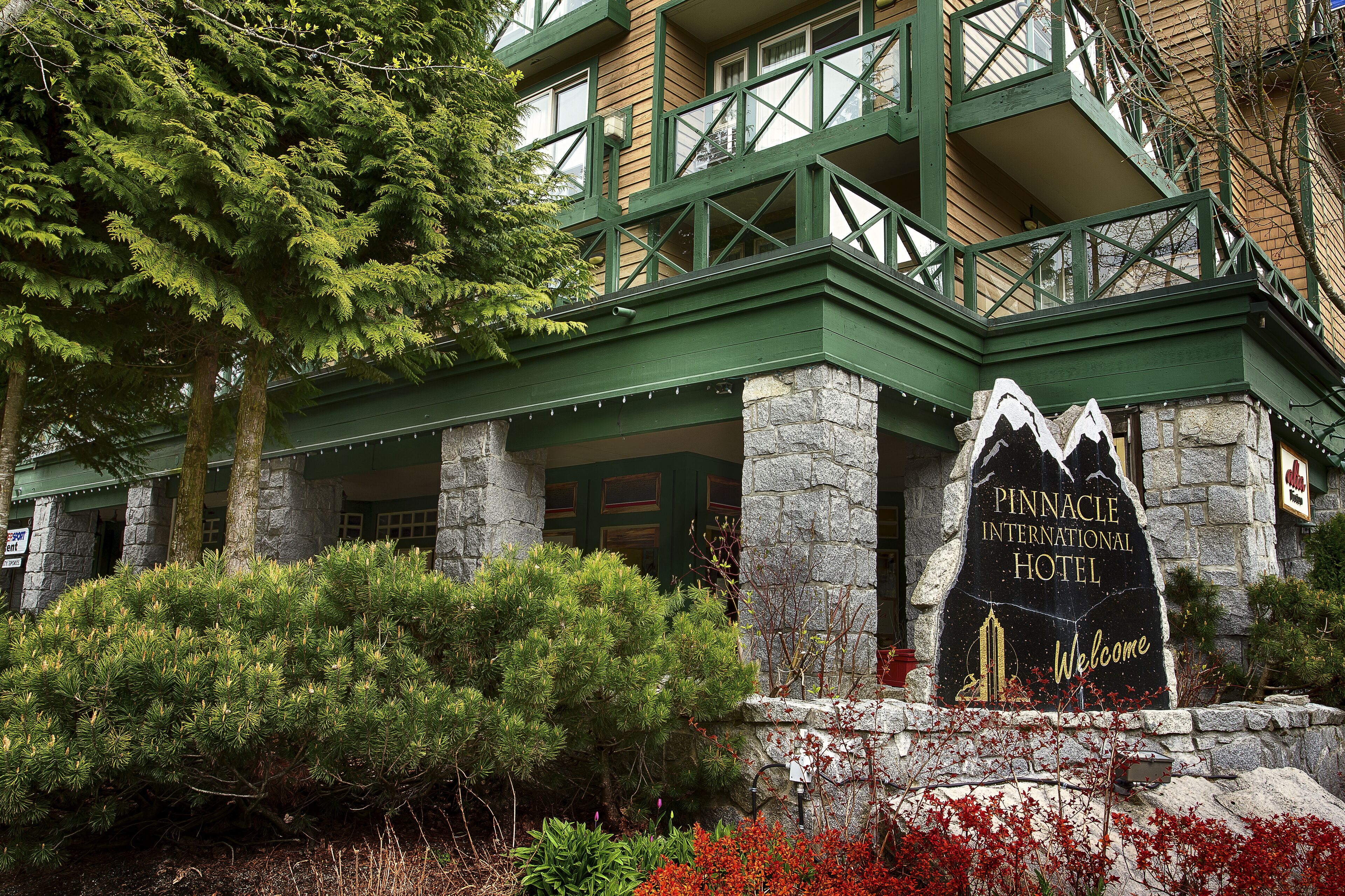 Entrada del Hotel Pinnacle International, con pilares de piedra y techo verde.