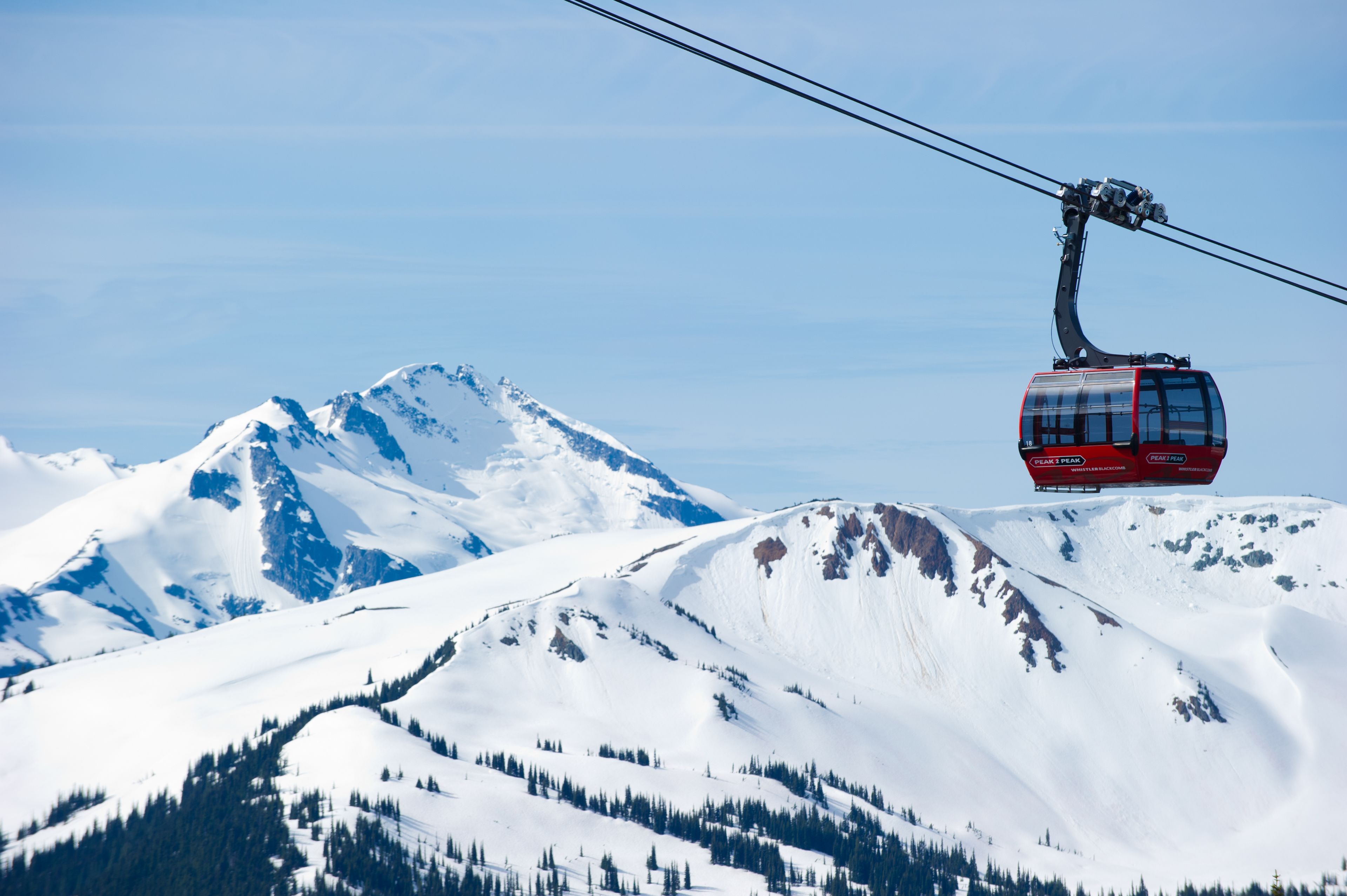 A cable car ascending a snow-covered mountain.