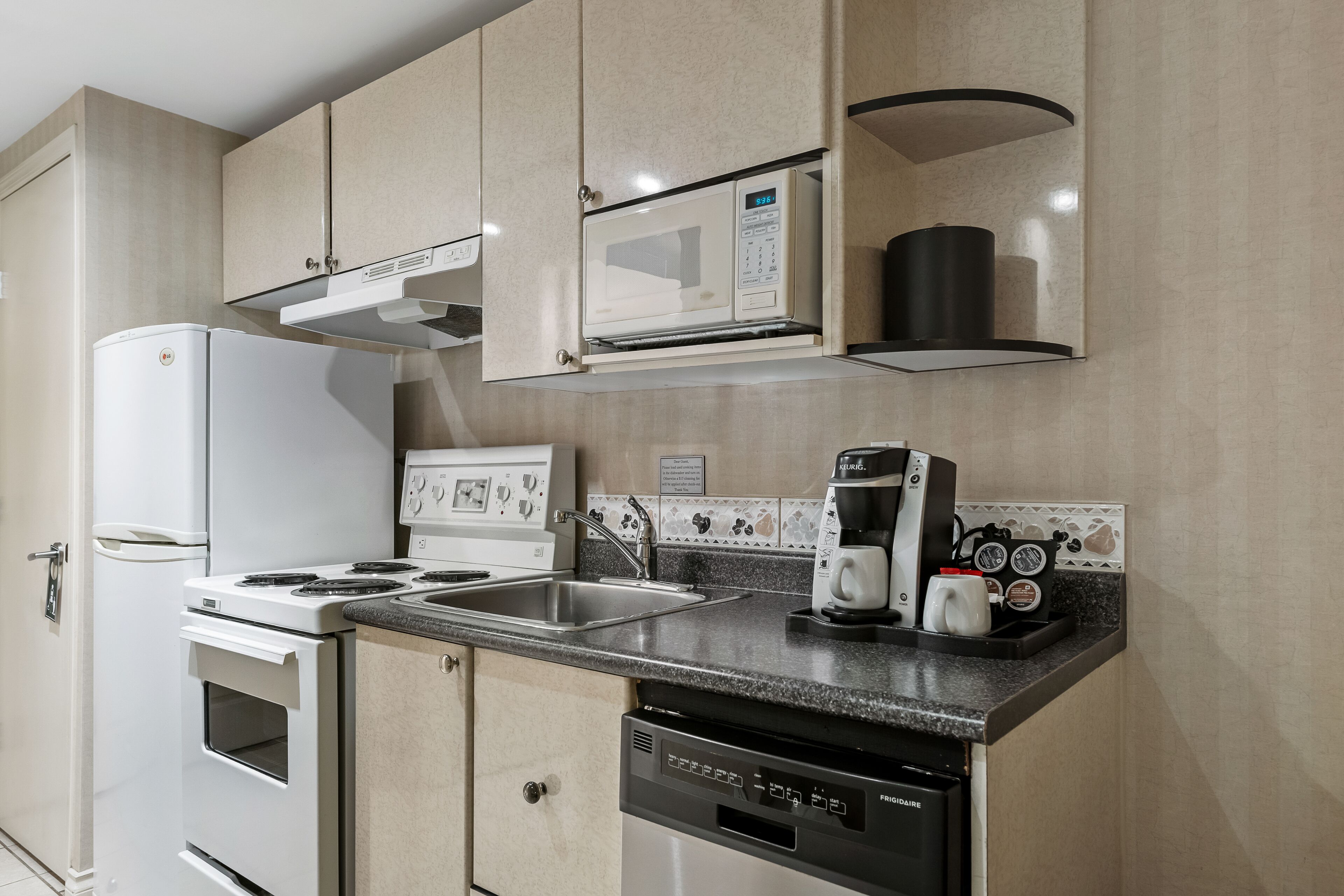 Una cocina compacta con un refrigerador blanco, estufa, microondas y lavavajillas.