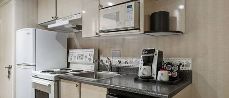 Una cocina compacta con un refrigerador blanco, estufa, microondas y lavavajillas.