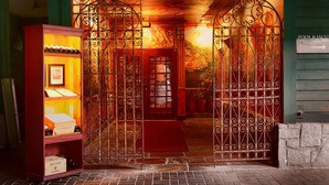 L’entrée d’un hôtel, avec des grilles en fer forgé richement décorées, un tapis rouge et un sol en briques.