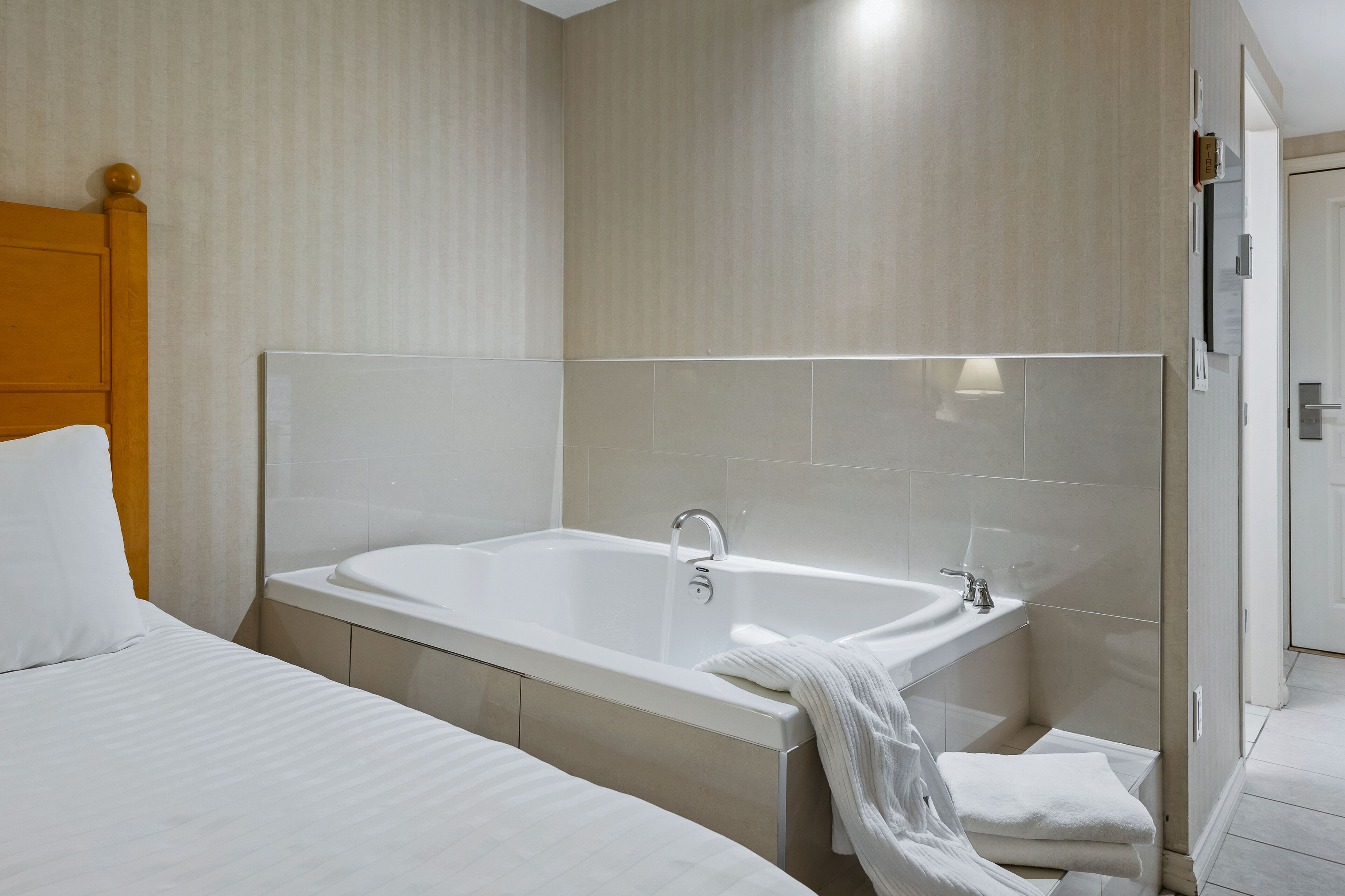 Un baño de hotel moderno con una bañera grande, una zona de ducha separada y un cabecero de madera.