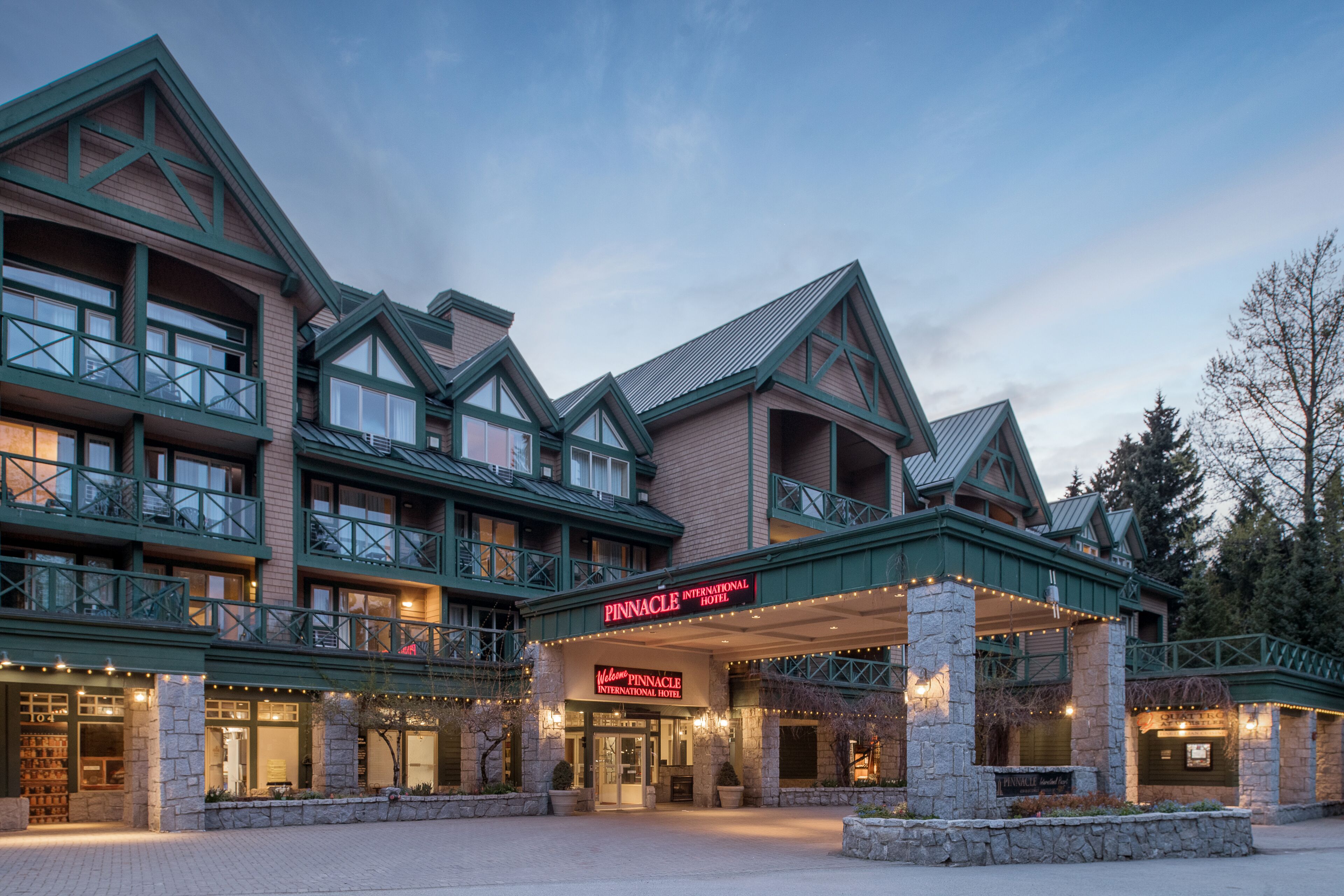 A multi-story hotel with a prominent entrance, stone facade, and green accents.
