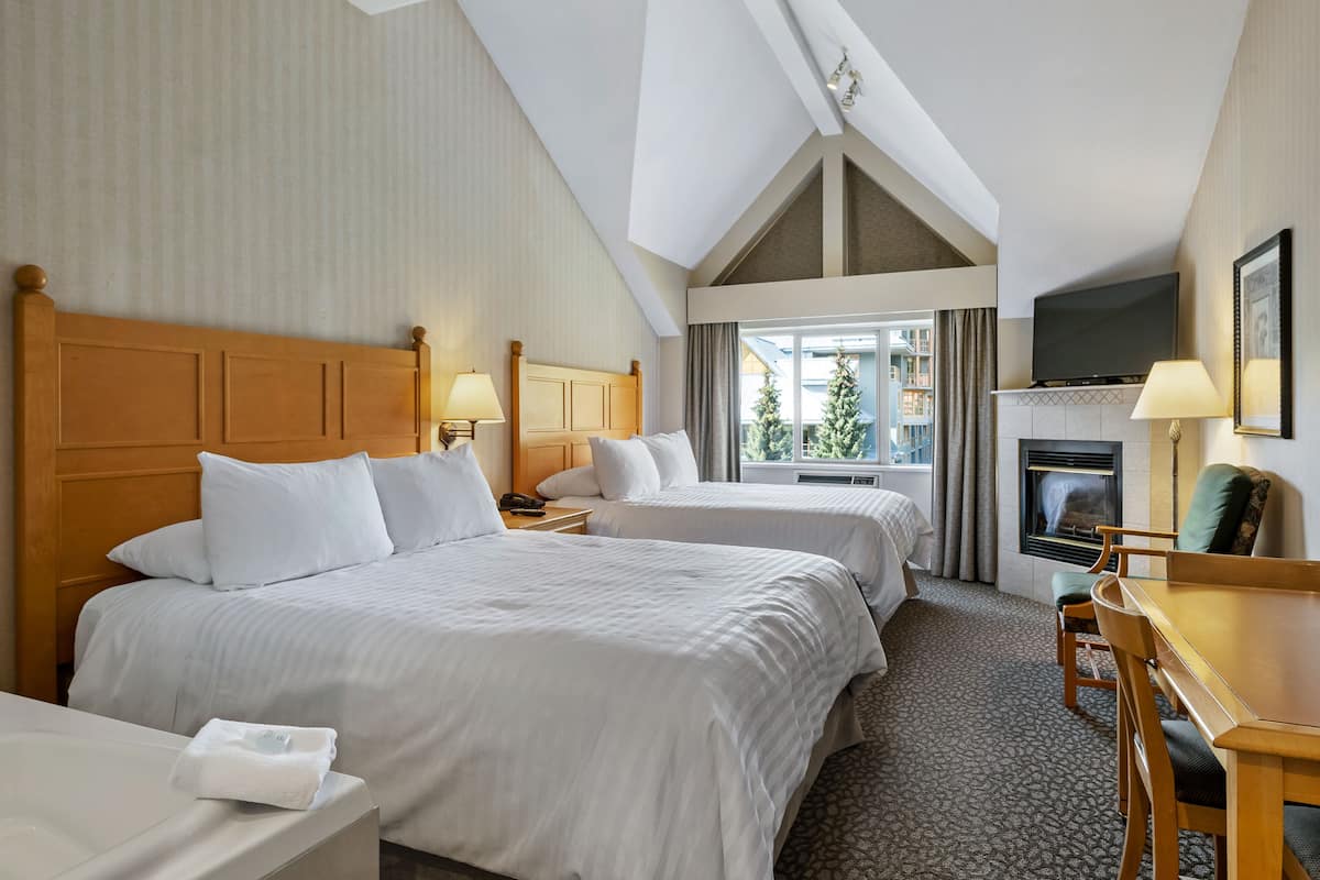 Een hotelkamer met twee bedden, een bureau, een open haard en een televisie.