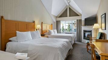 A hotel room with two beds, a desk, a fireplace, and a TV.