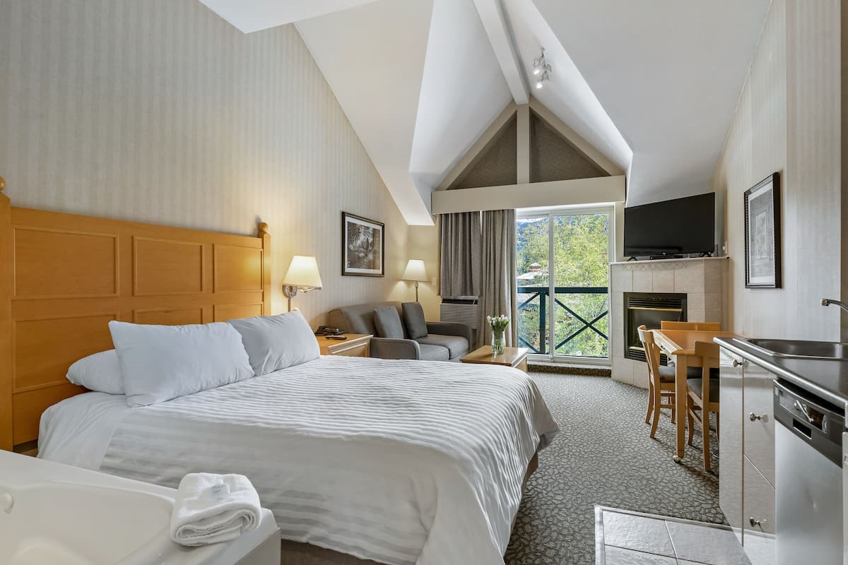 Een hotelkamer met een groot bed, een bureau, een televisie en een open haard.