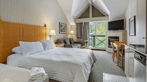 Ein Hotelzimmer mit einem großen Bett, einem Schreibtisch, einem Fernseher und einem Kamin.