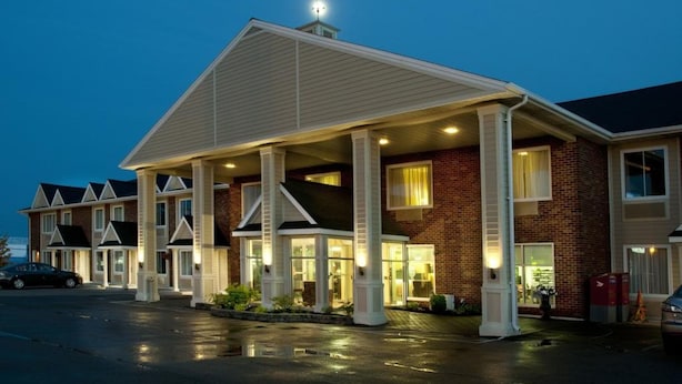Un hotel con entrada cubierta, múltiples ventanas y fachada de ladrillo.