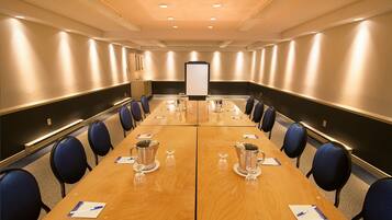 A conference room with a long table, chairs, a projector screen, and presentation materials.