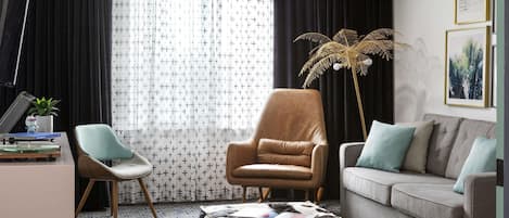 A living room with a sofa, armchair, ottoman, and a floor lamp.