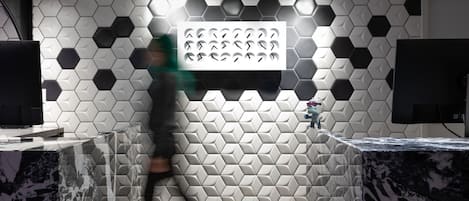 Un interior moderno con azulejos hexagonales en la pared, una lámpara central y un televisor de pantalla plana.