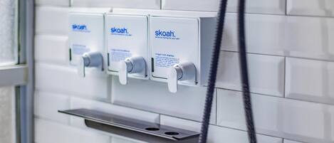 A wall-mounted shower with three separate controls, each labeled 'skoh.'