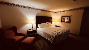 A hotel room with a bed, two bedside tables with lamps, a chair, and a framed picture on the wall.